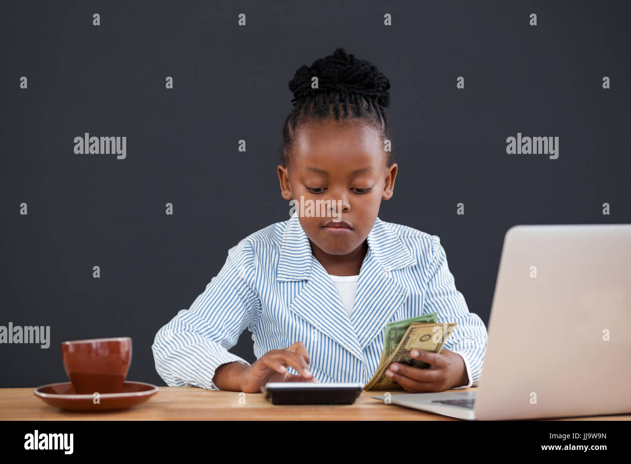 Serious businesswoman calculating paper currency at desk in office Stock Photo