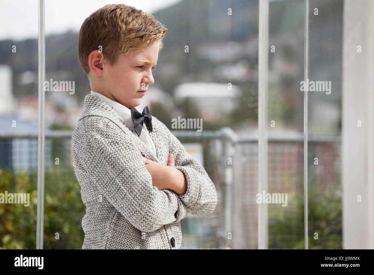 Thoughtful businessman looking away while standing with arms crossed at ...