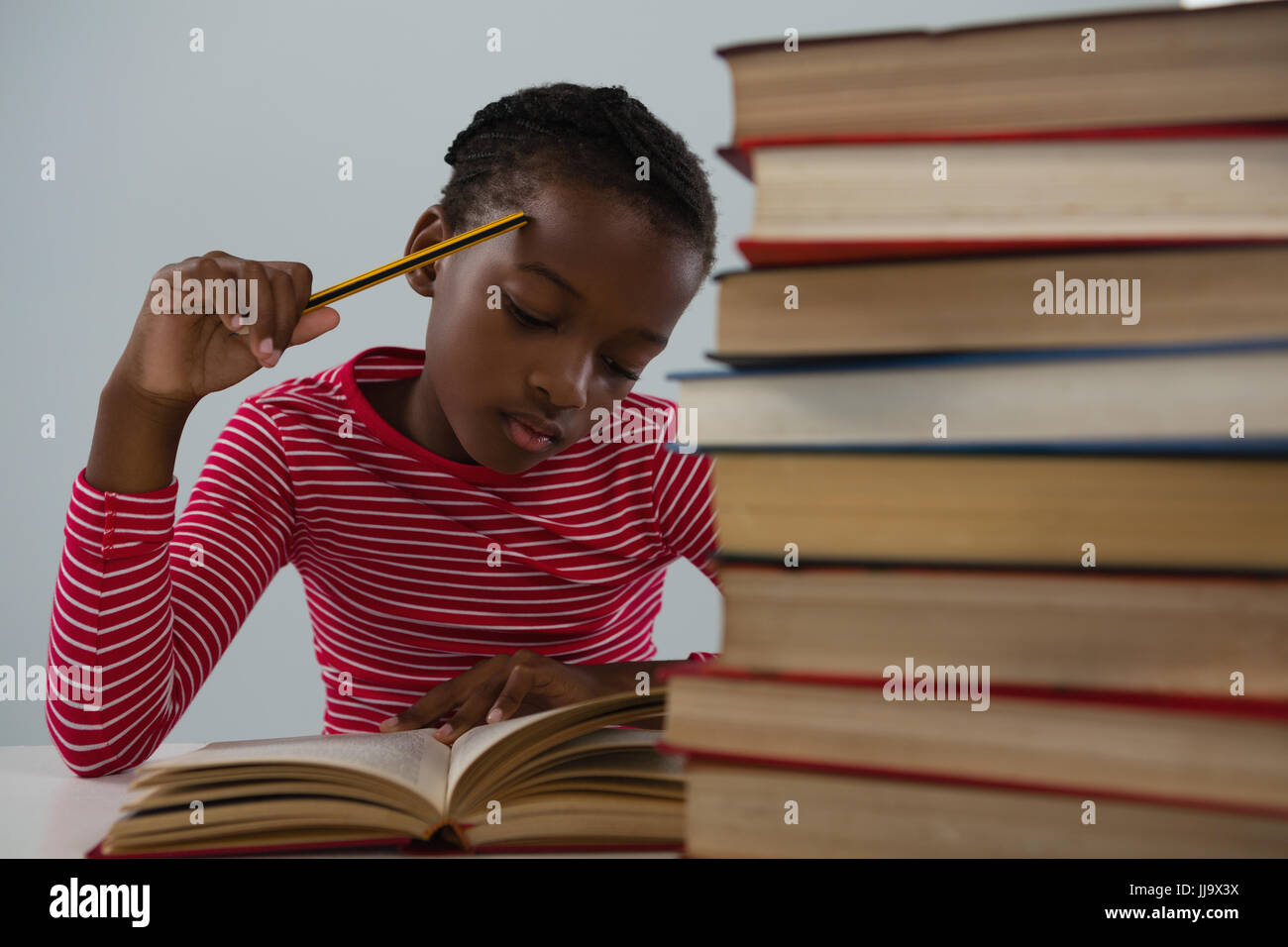 Attentive schoolgirl doing his homework against white background Stock ...