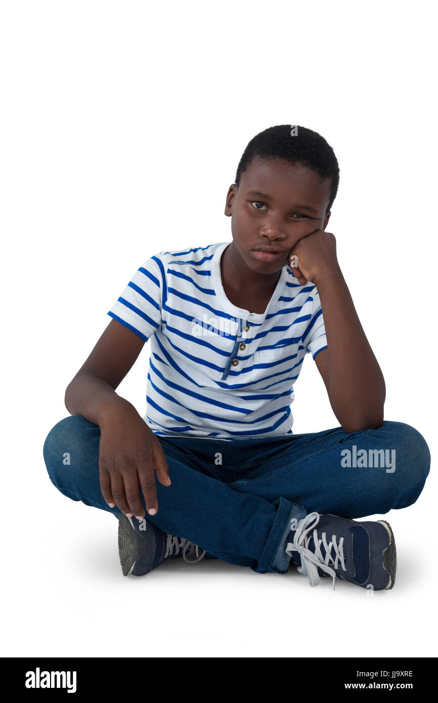 Sad boy sitting on floor against white background Stock Photo