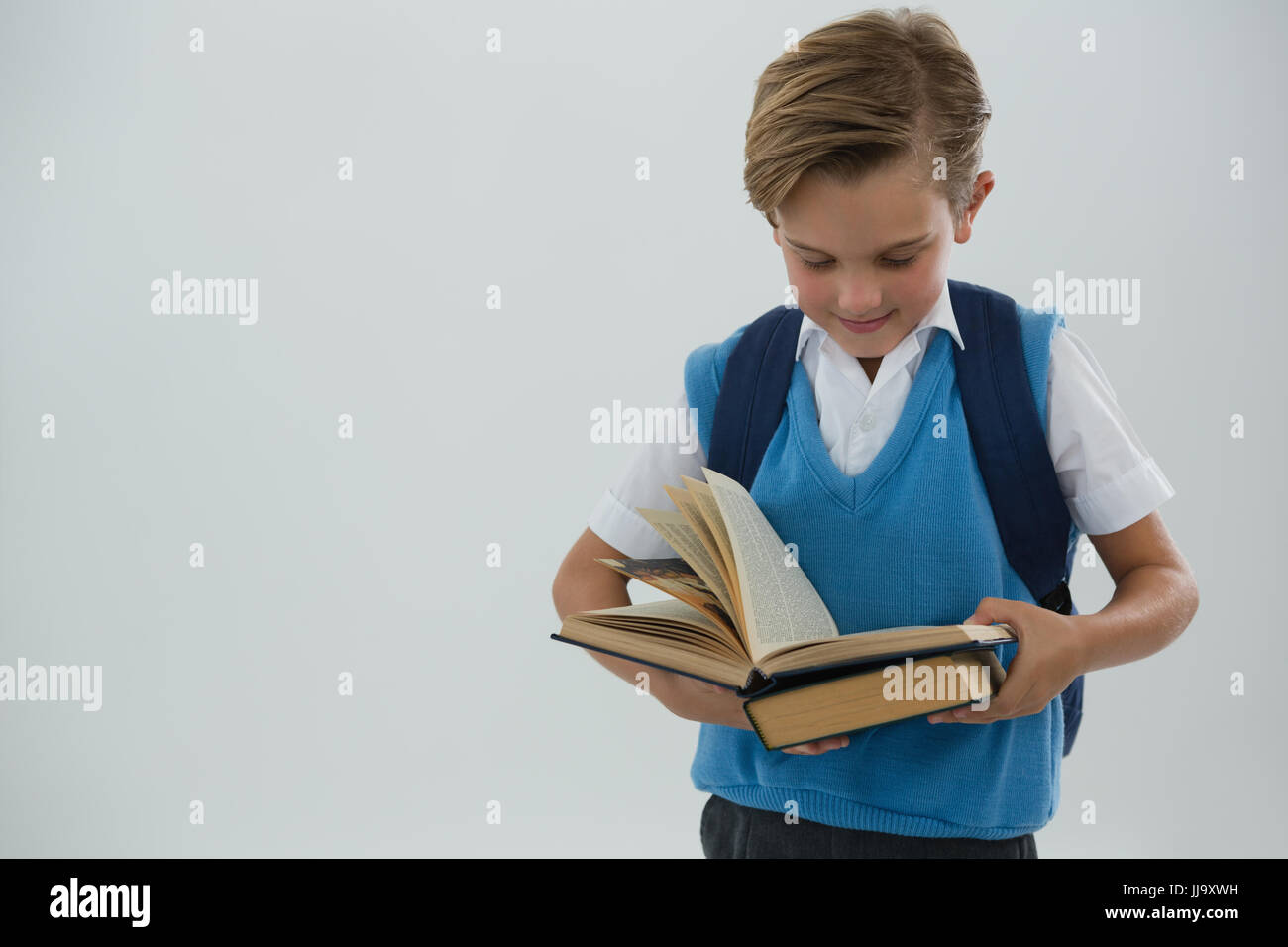 Attentive schoolboy reading book against white background Stock Photo ...