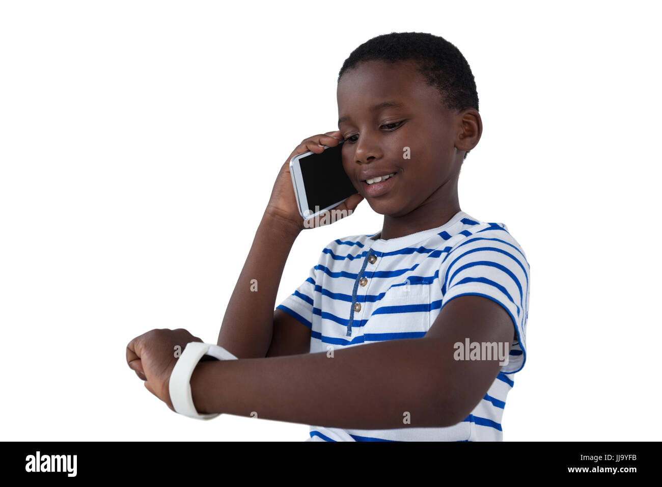 Boy looking at his smart watch while talking on mobile phone against white background Stock Photo