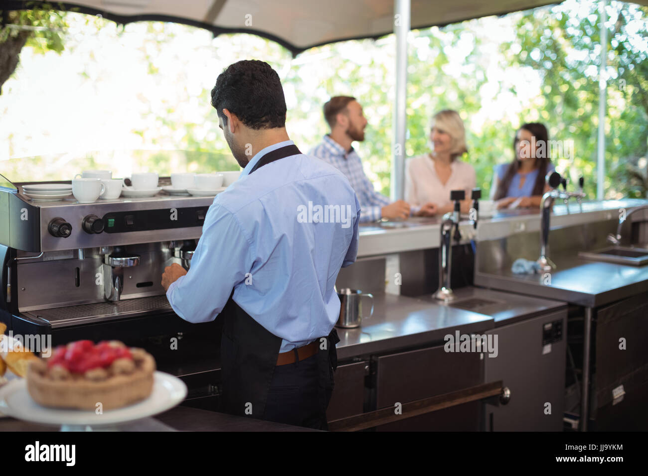 Waiter using tamper to press ground coffee into a portafilter in