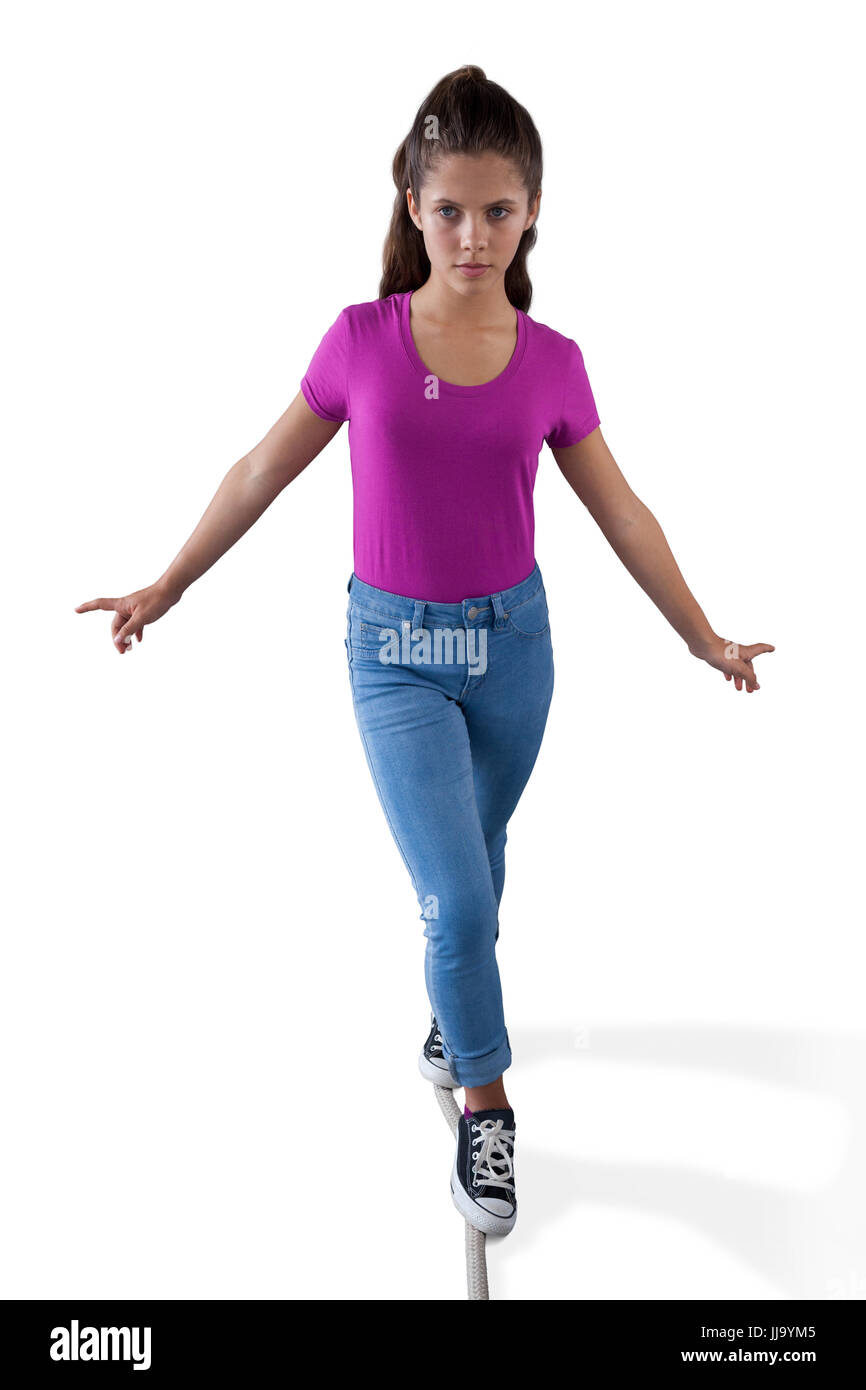 Girl walking on a tight rope and trying to keep her balance against white background Stock Photo