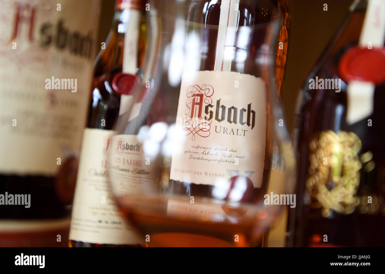 Ruedesheim, Germany. 30th June, 2017. ILLUSTRATION - A bottle reading 'Asbach Uralt' can be seen through a glass with brandy at the Asbach brandy distillery in Ruedesheim, Germany, 30 June 2017. Whether as a praline, in typical Ruedesheimer coffee or pure in a bulbous glass: The brandy of Asbach Uralt can be found at every corner in Ruedesheim. The distillery was founded 125 years ago. Photo: Arne Dedert/dpa/Alamy Live News Stock Photo