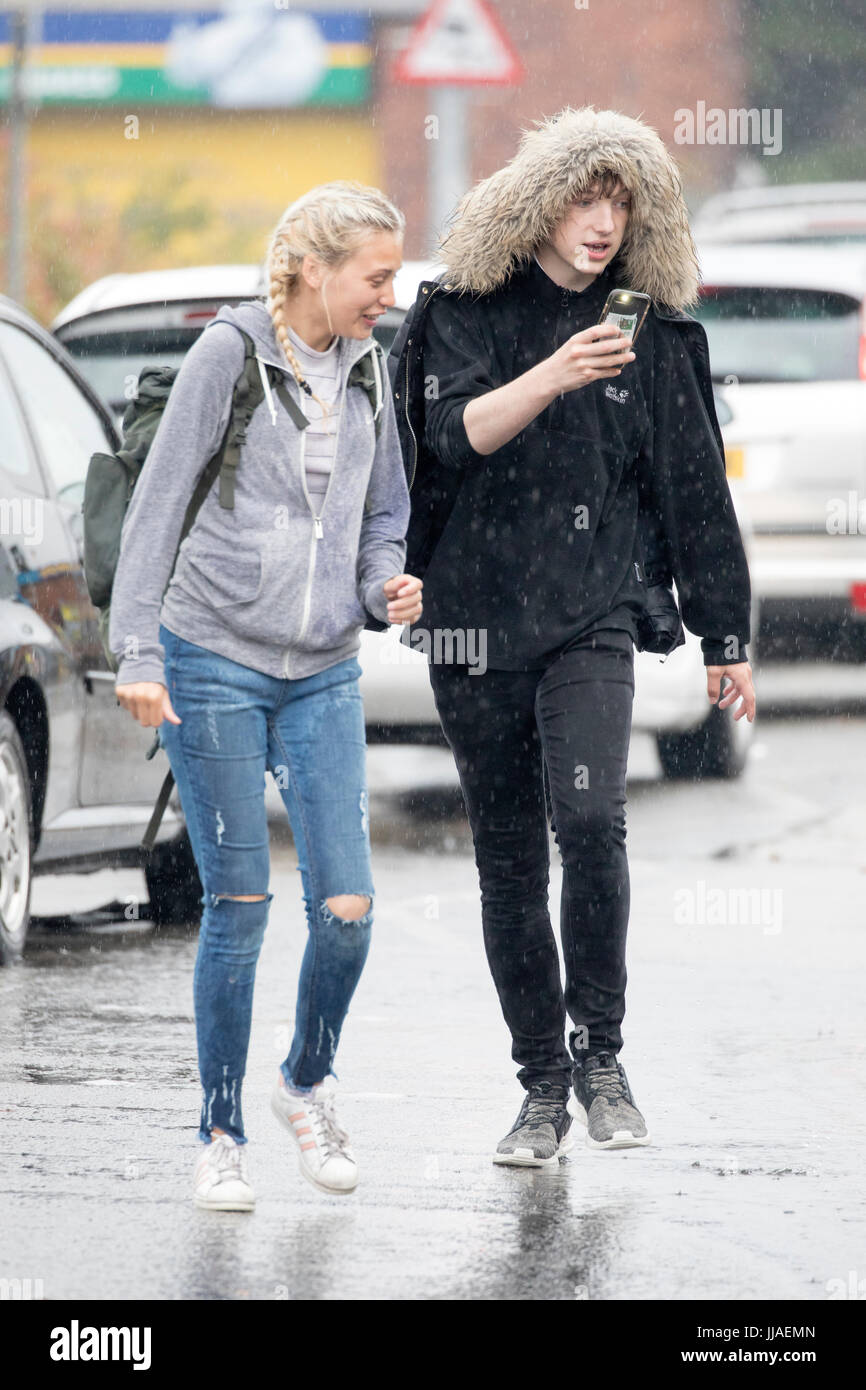 People caught out by torrential rain and flash flooding during a summer storm as they walk through flooded streets on the A525 road in the coastal resort town of Rhyl, Denbighshire, Wales, UK Stock Photo