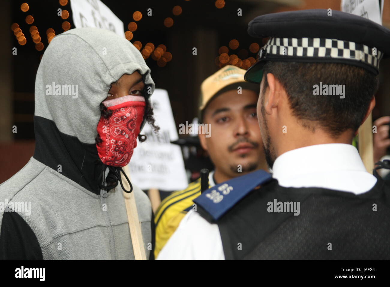 London, UK. 19th July 2017. A policeman faces a couple of young protesters. Protests take place outside the Kensington and Chelsea Council building as the council meets to discuss the Grenfell disaster a month after it happened. Roland Ravenhill/Alamy Live News. Credit: Roland Ravenhill/Alamy Live News Stock Photo