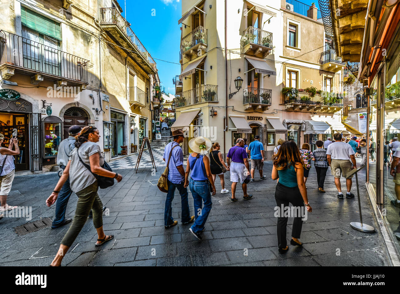 The picturesque old town section of Taormina with tourists window shopping on the Italian island of Sicily Stock Photo
