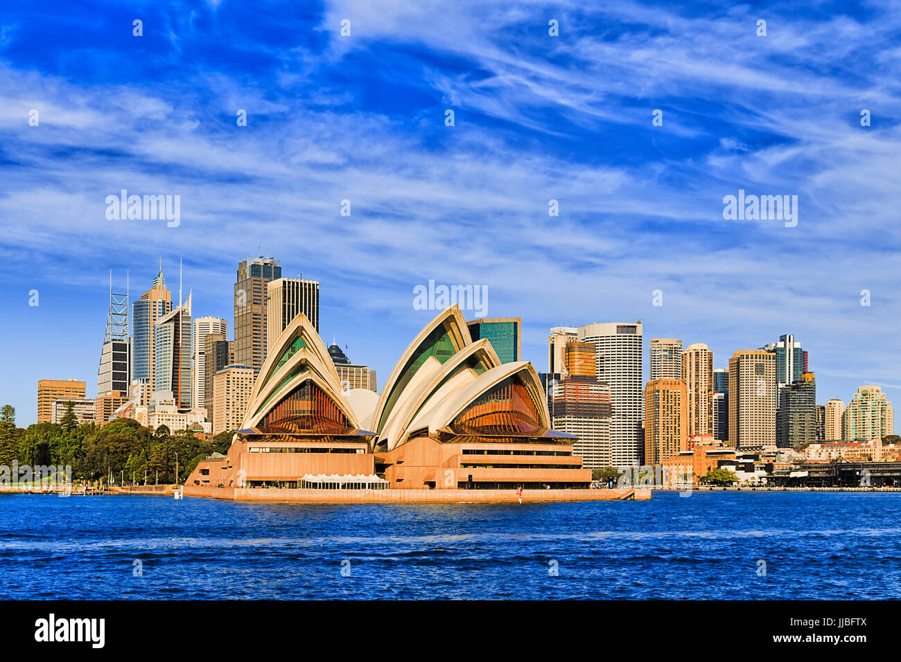 Modern cityline of Sydney city CBD landmarks as seen from passenger ferry in mid harbour on a sunny bright day under blue sky. Stock Photo