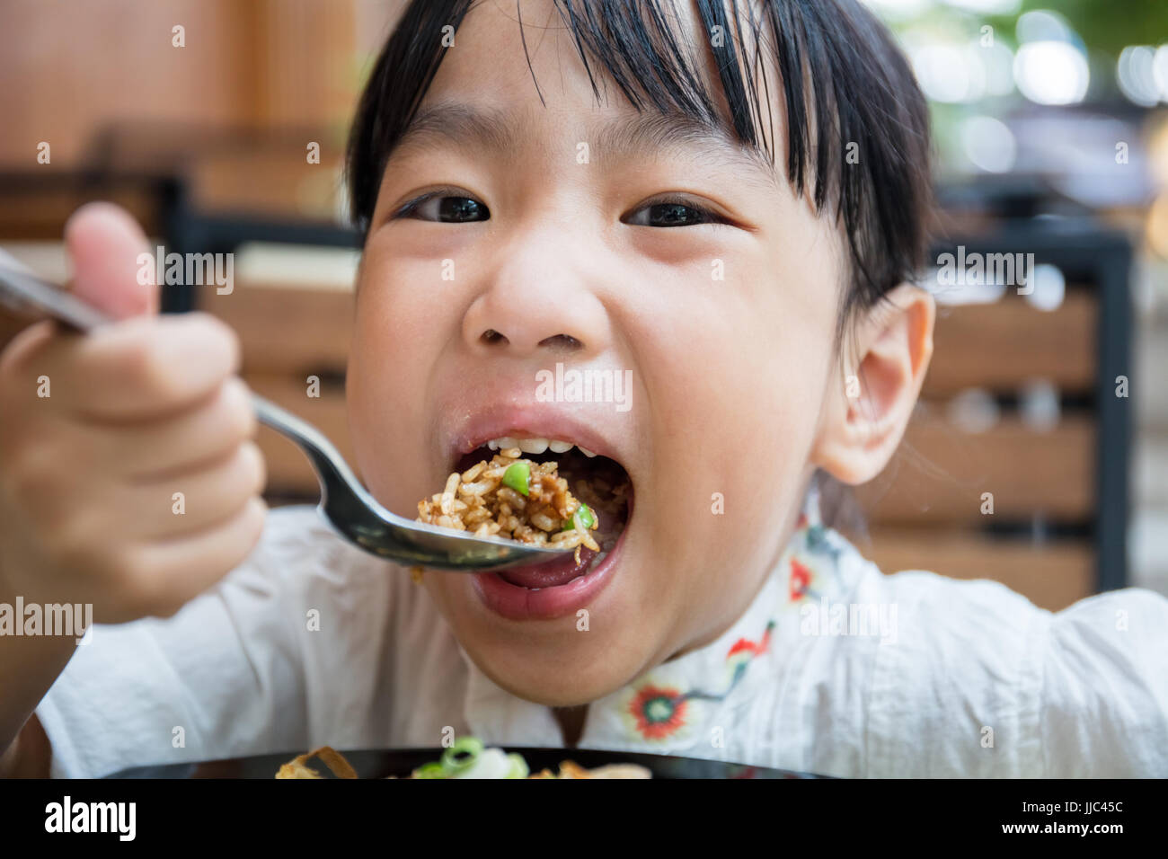 Asian Chinese little girl eating fried rice at outdoor cafe Stock Photo Alamy