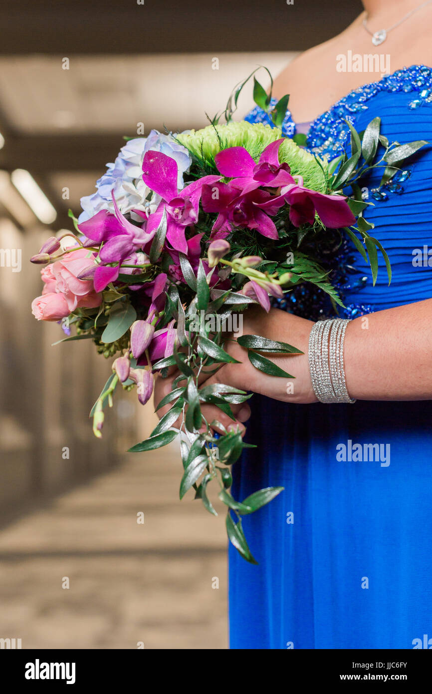 Teen girl wearing blue prom dress holding pastel floral arrangement ...