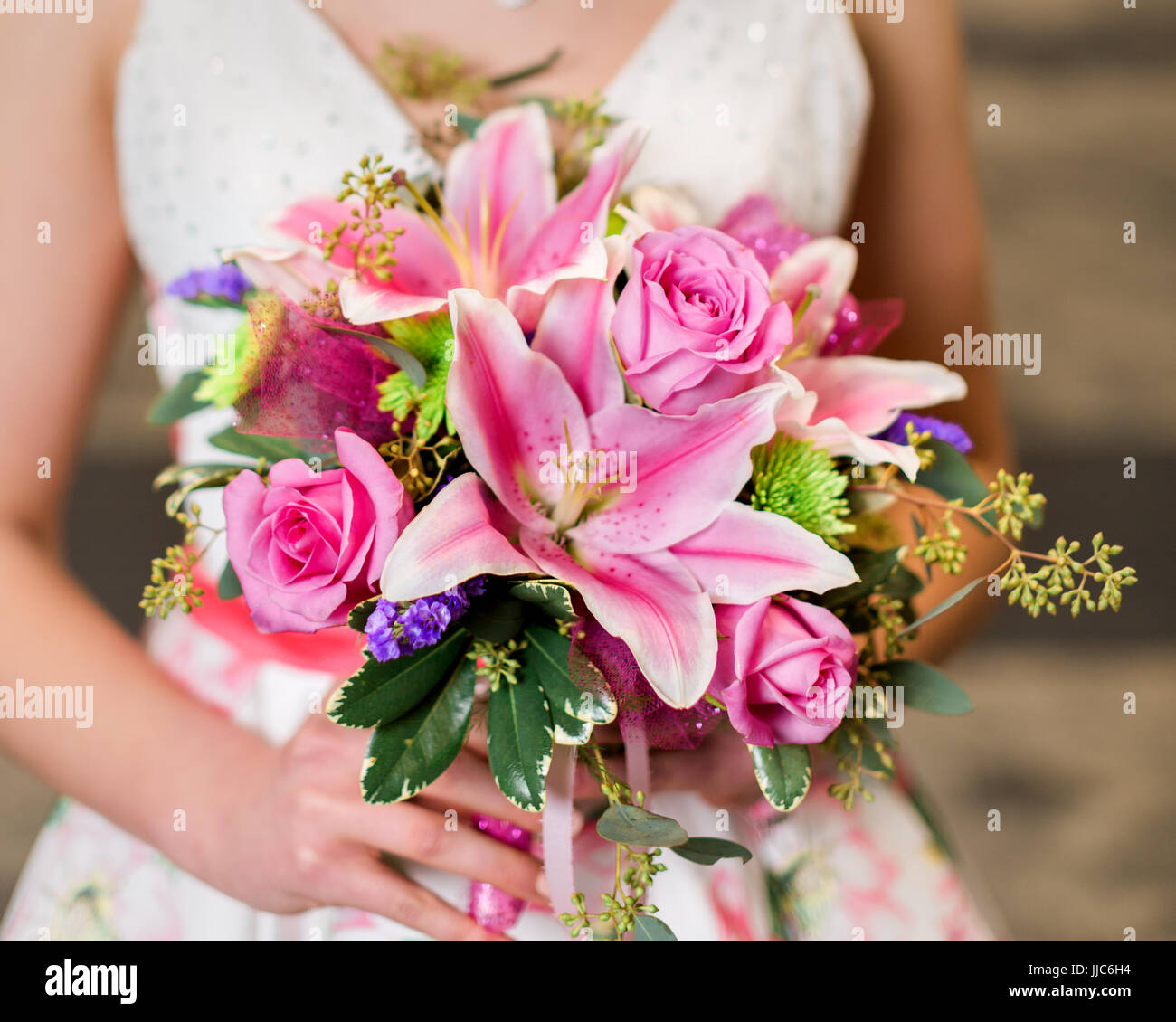 Teen girl holding pink rose and lily bouquet getting ready for prom. Stock Photo