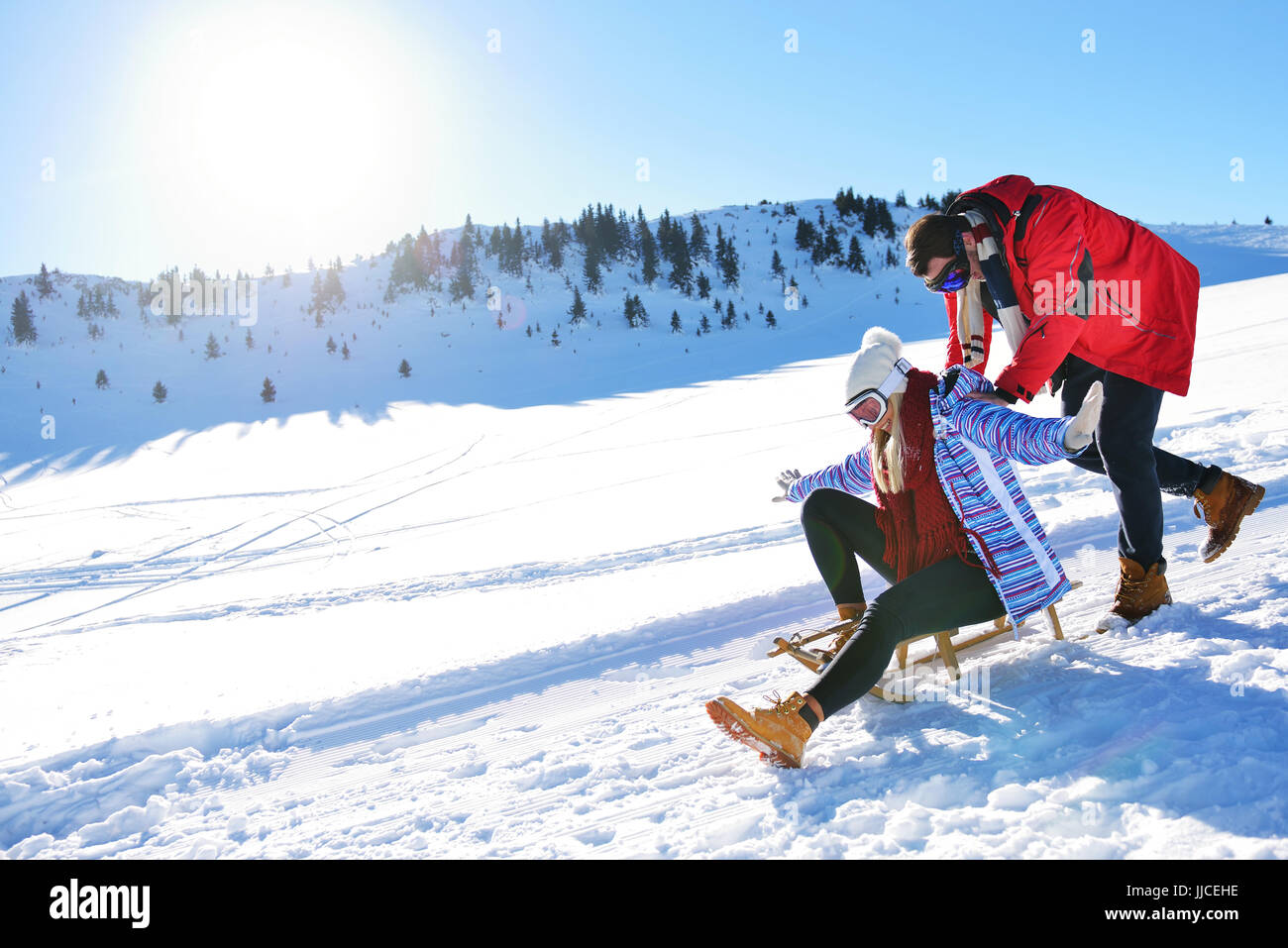 Young Couple Sledding And Enjoying On Sunny Winter Day Stock Photo