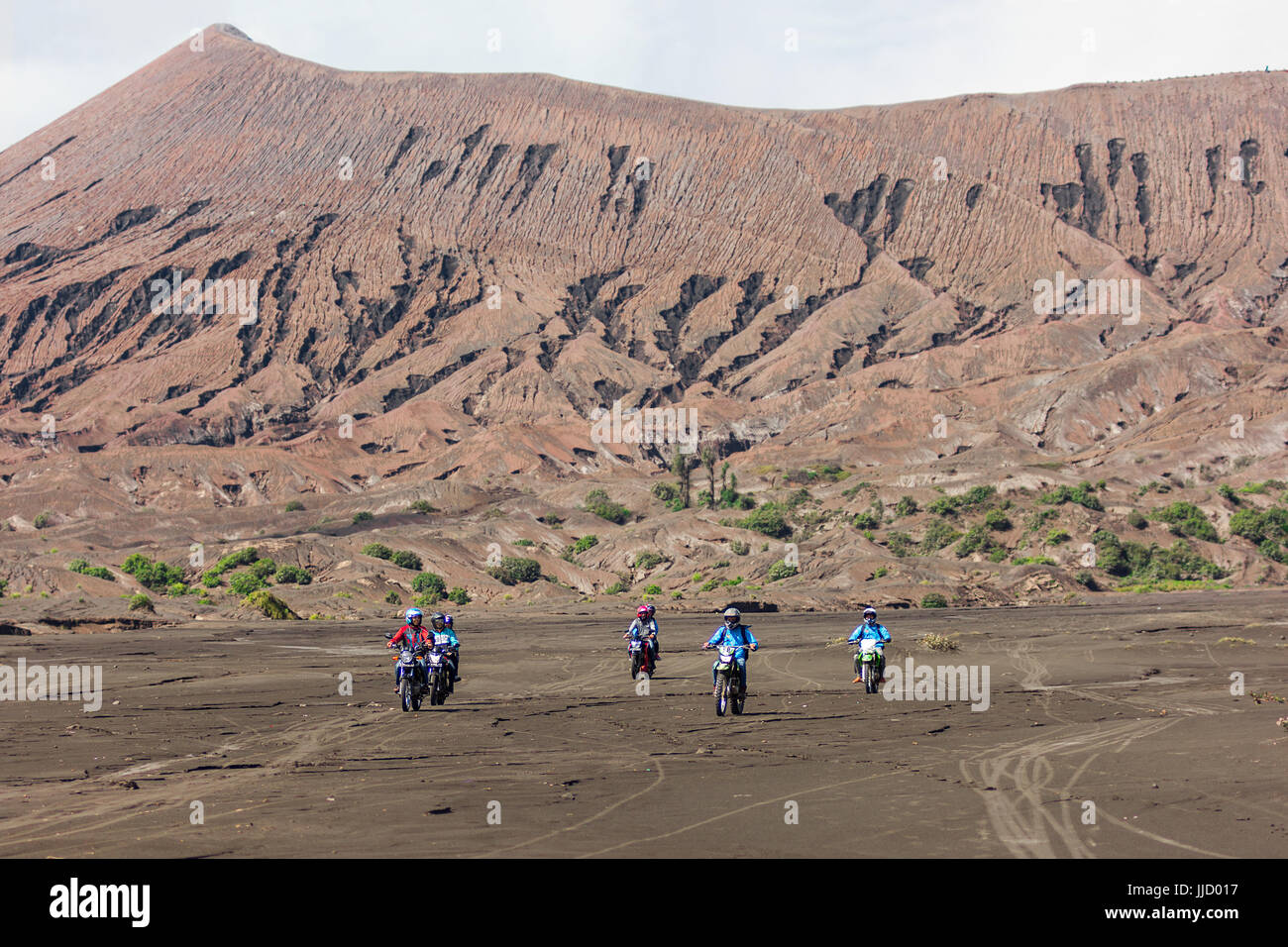 Group of off road motor bikers ride across the ash flats of Mt Bromo, Java, Indonesia. Stock Photo