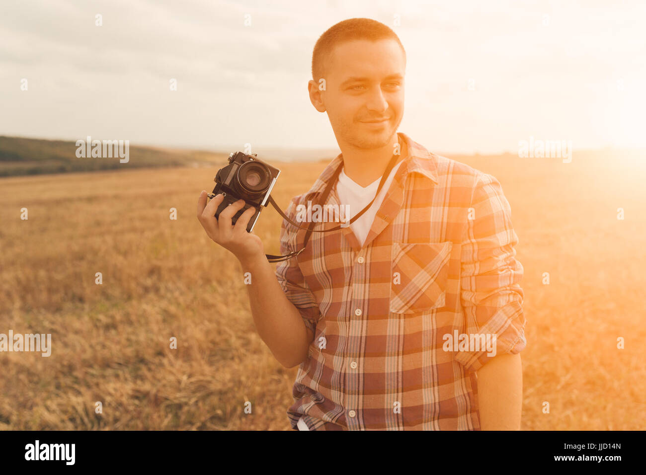 Portrait of attractive male photographer outdoors at sunset. Young man with a camera in hand Stock Photo