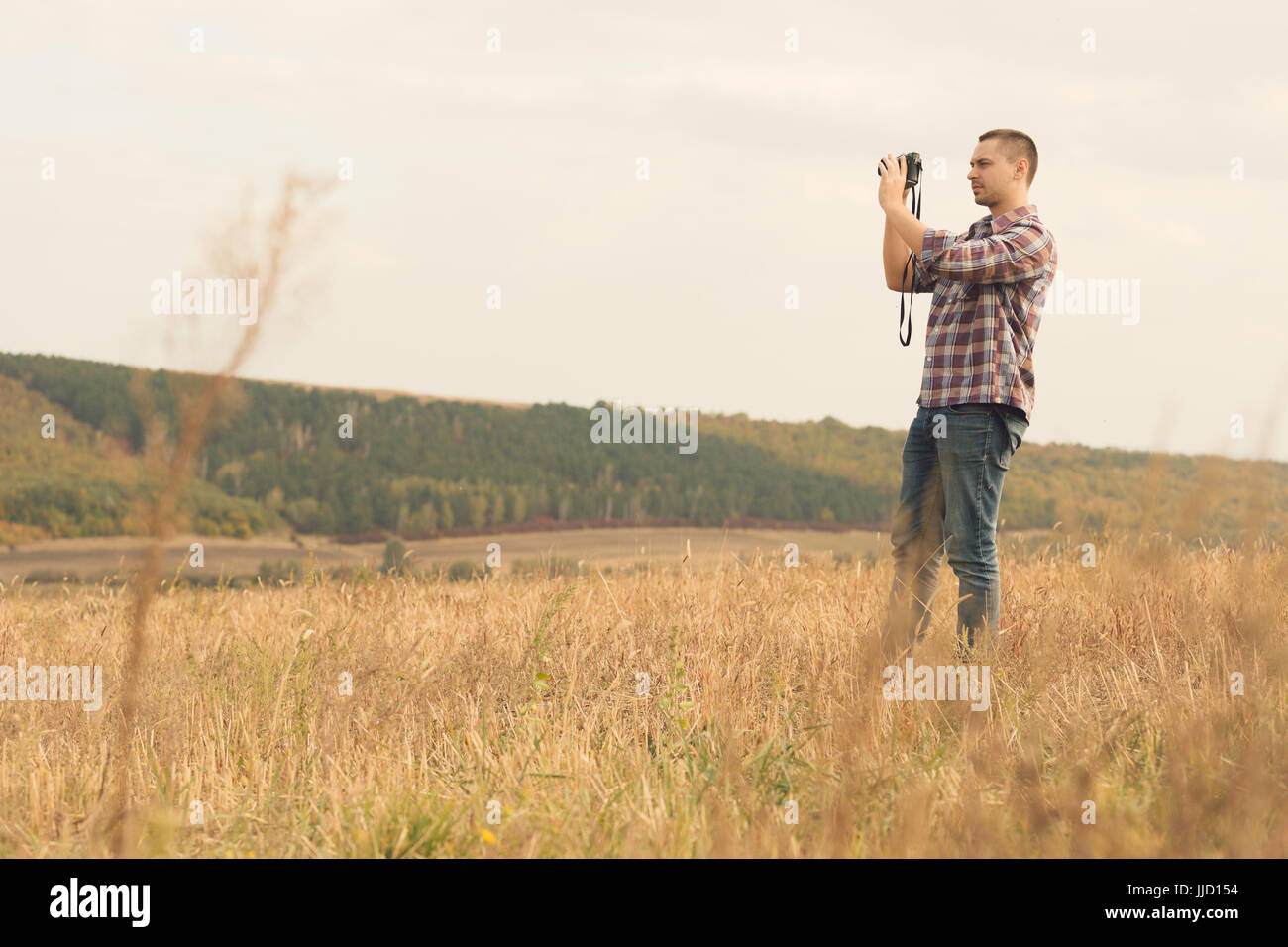 Portrait of attractive male photographer outdoors at sunset. Young man with a camera in hand Stock Photo