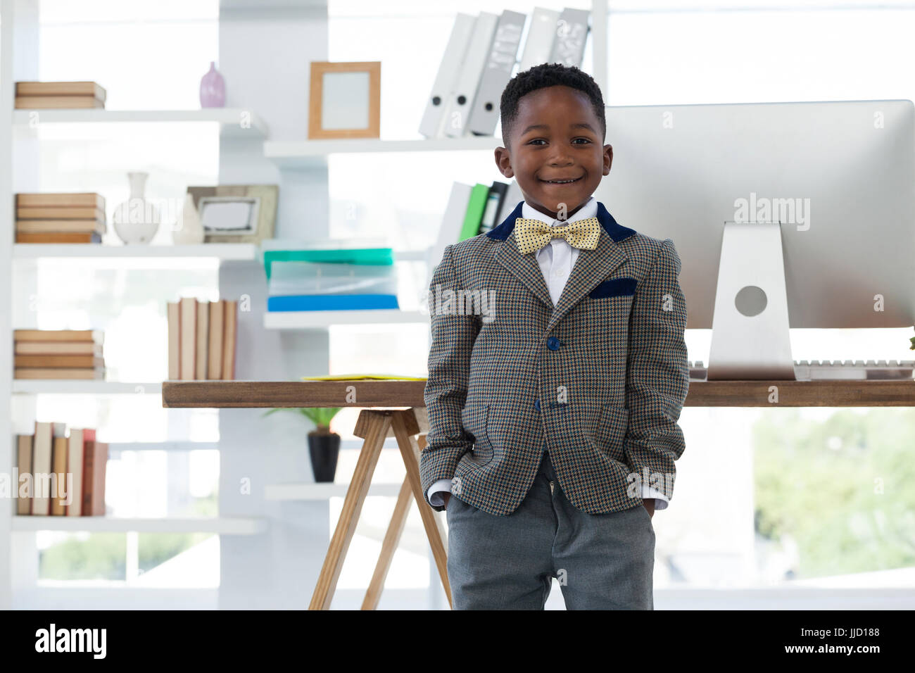 Portrait of boy imitating at businessman standing in office Stock Photo