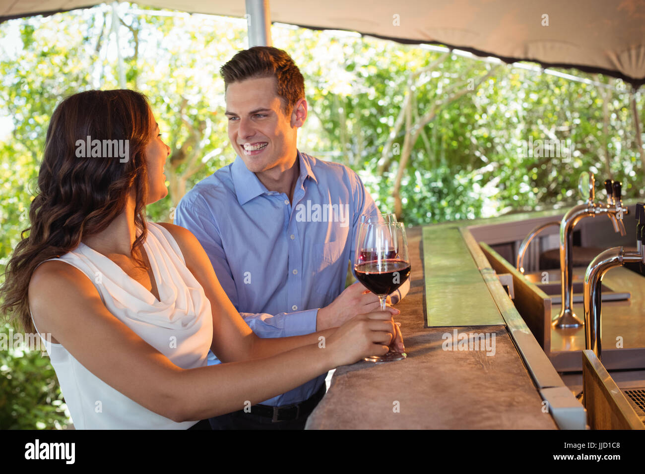 Couple interacting while having a glass of red wine at counter Stock ...