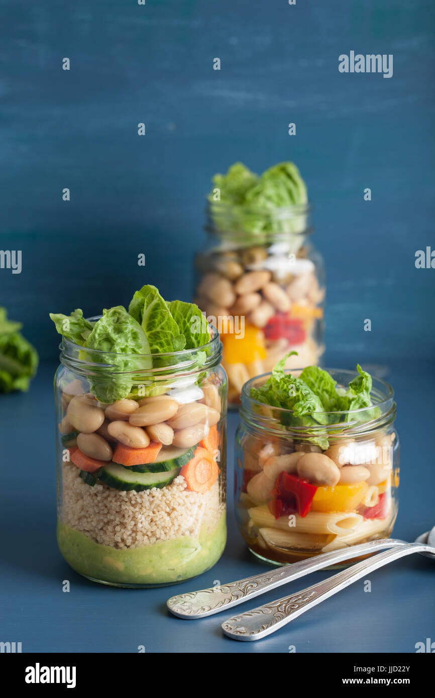 vegan couscous and pasta salad in mason jars with vegetables beans