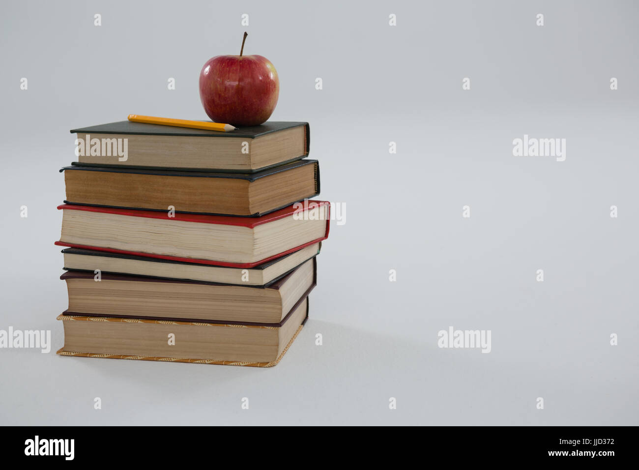 Book Stack With Ruler Apple Apple and pencil on book stack on white background Stock Photo - Alamy