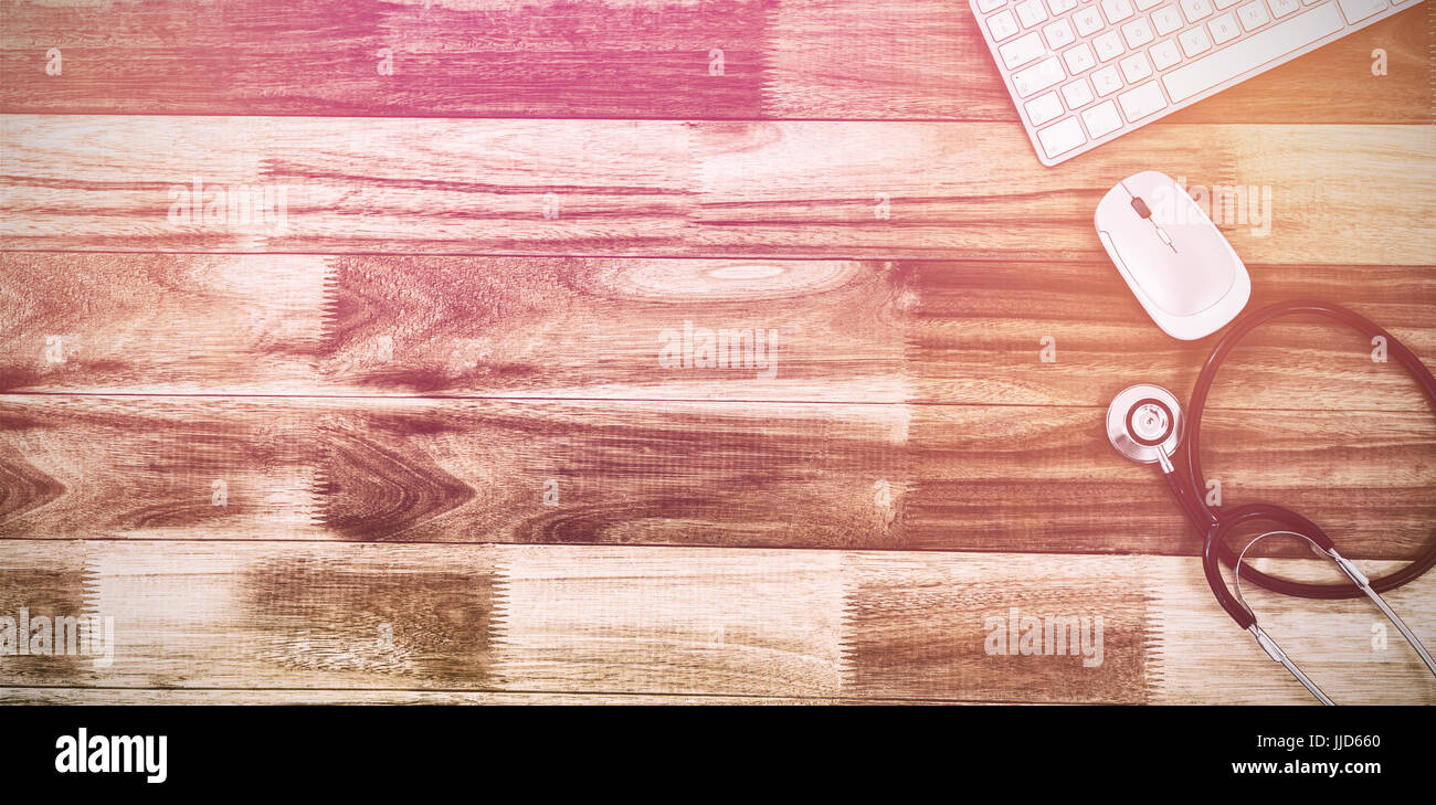 Overhead view of stethoscope with keyboard and mouse on wooden table ...