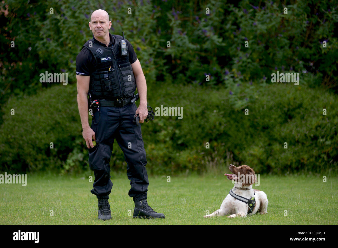Police dog handler and his dog perform for children at a school Stock