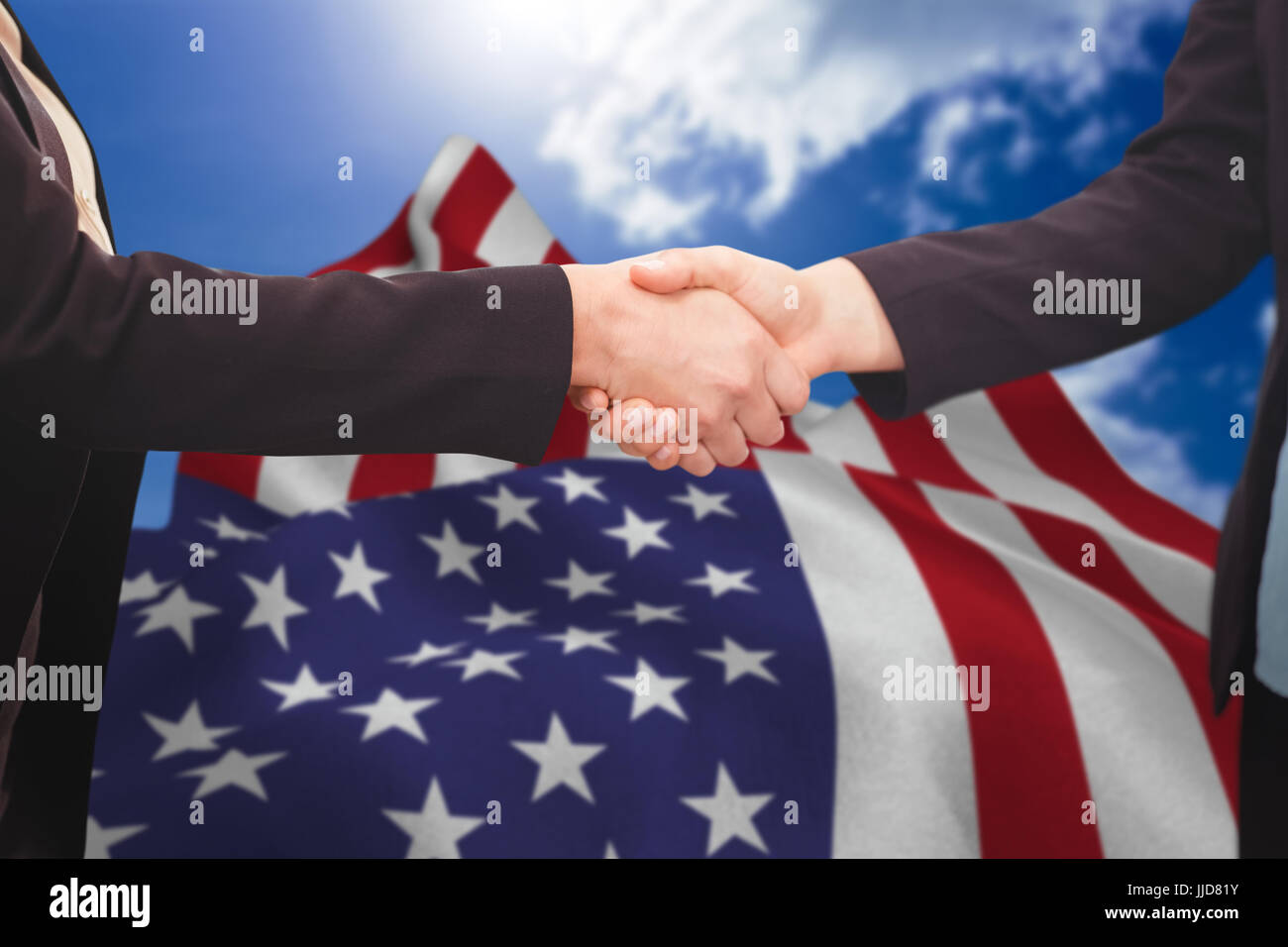Businessman shaking hands with colleague against blue sky Stock Photo