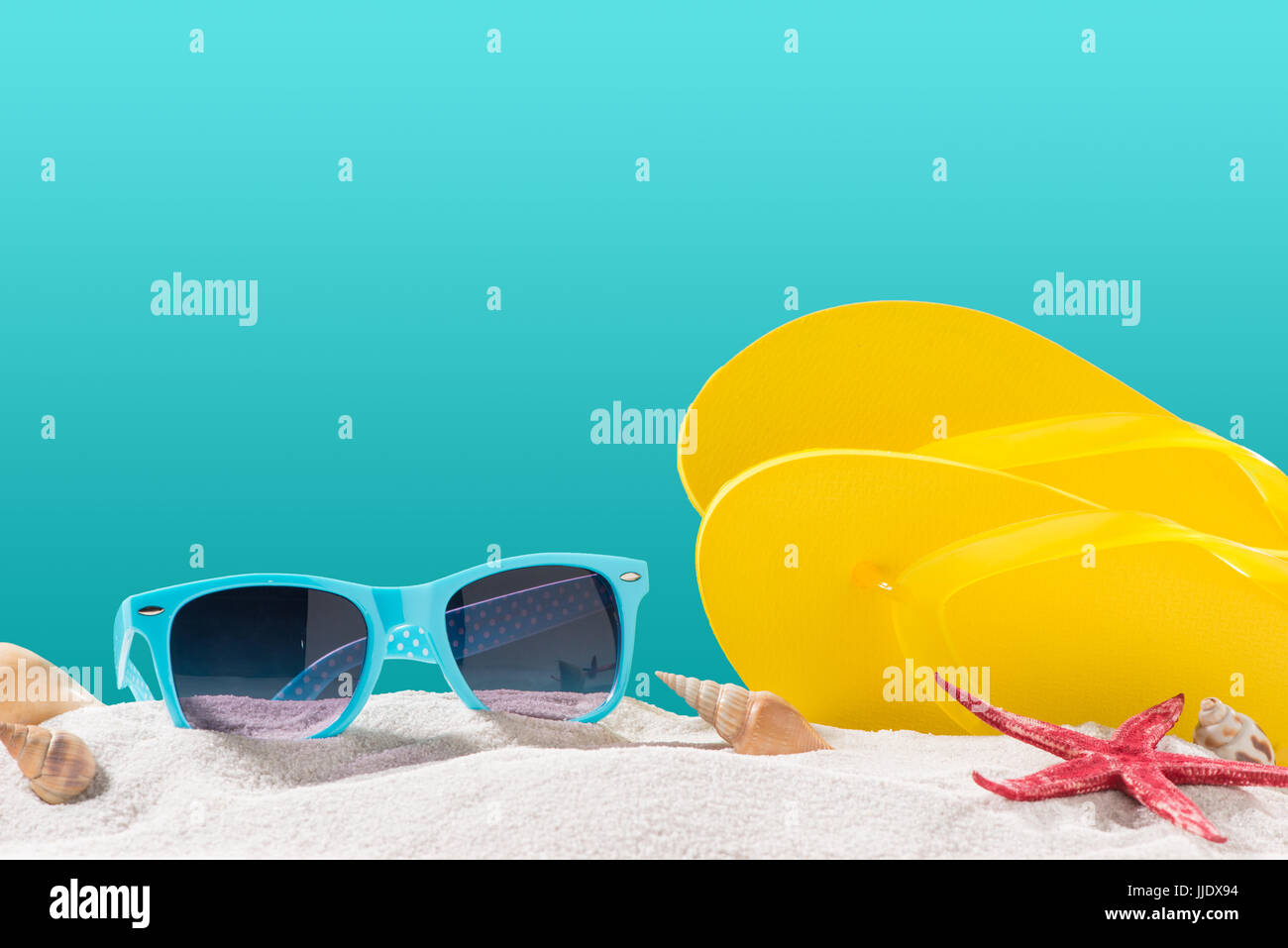 Yellow flip flops on beach against blue background Stock Photo - Alamy