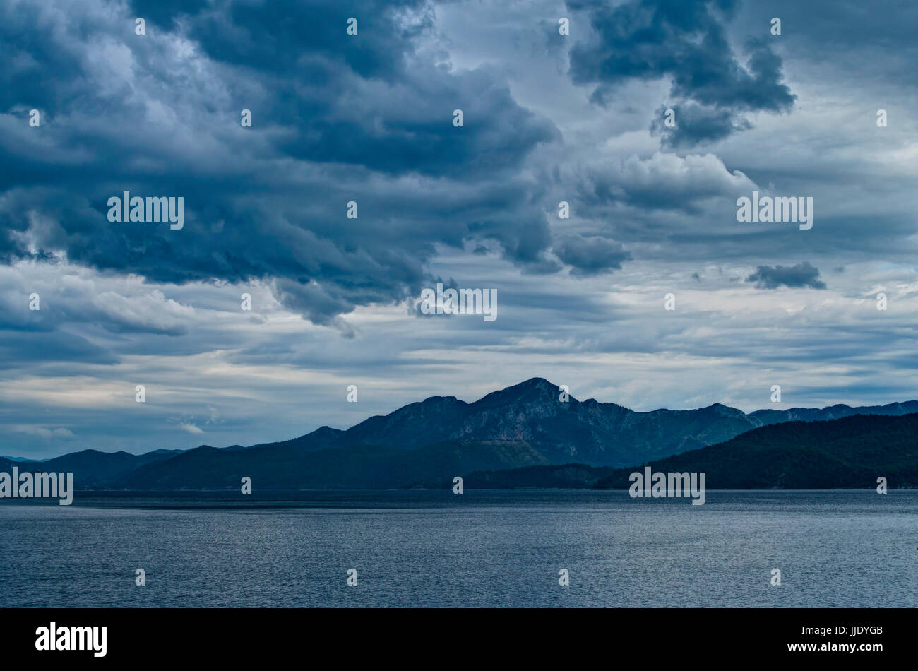 mountain range on island and Aegean sea during thunderstorm with dark dramatic clouds, Turkey Stock Photo