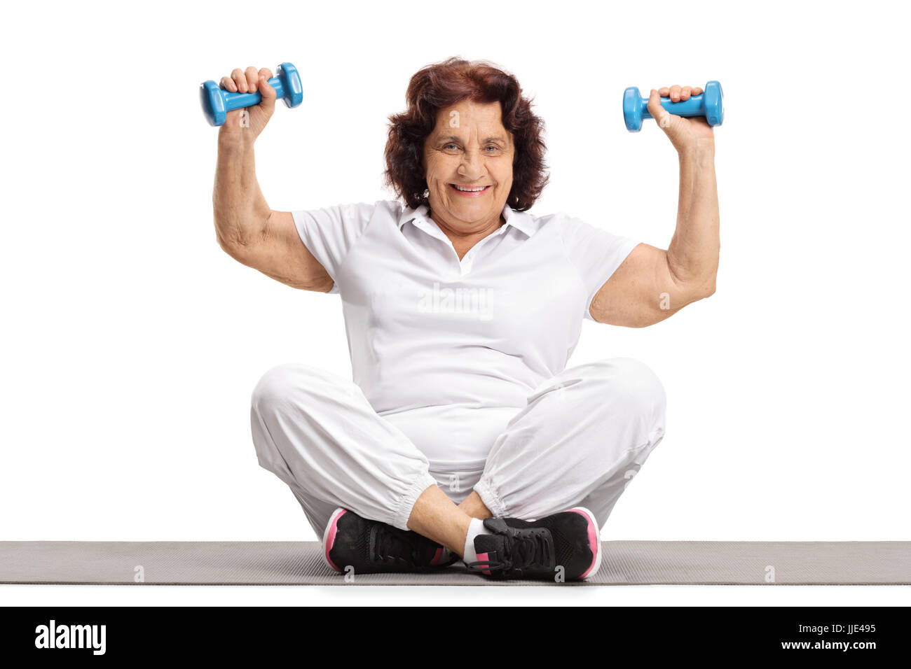 Elderly woman lifting dumbbells on an exercise mat isolated on white background Stock Photo