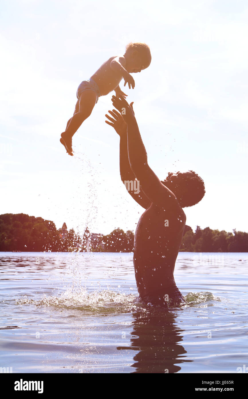 Happy family spending time together on a lake Throwing toddler up