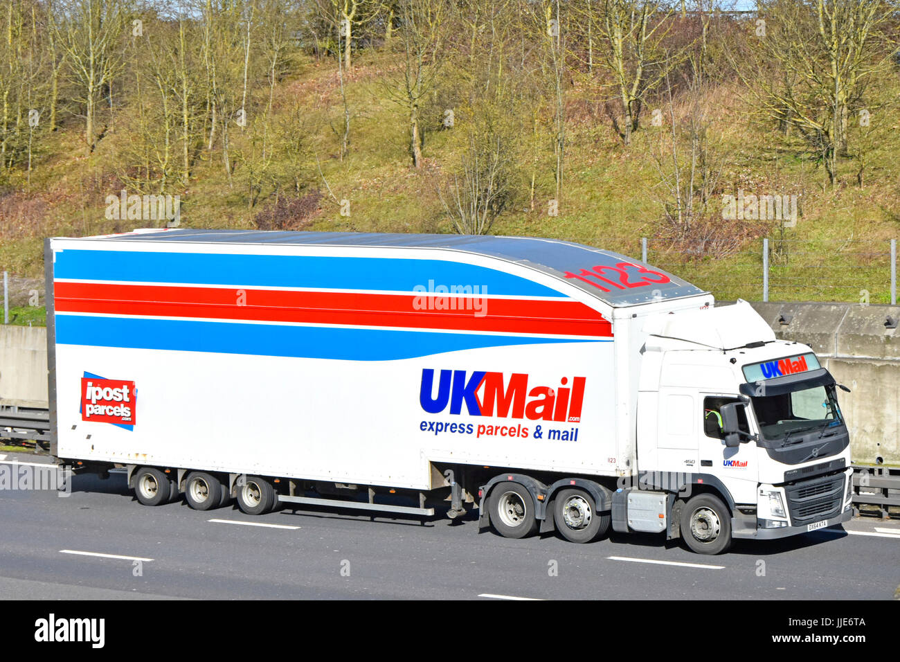 UKMail express parcels & mail logistics articulated trailer & hgv truck lorry driving along English motorway Essex England UK includes advert for ipost Stock Photo