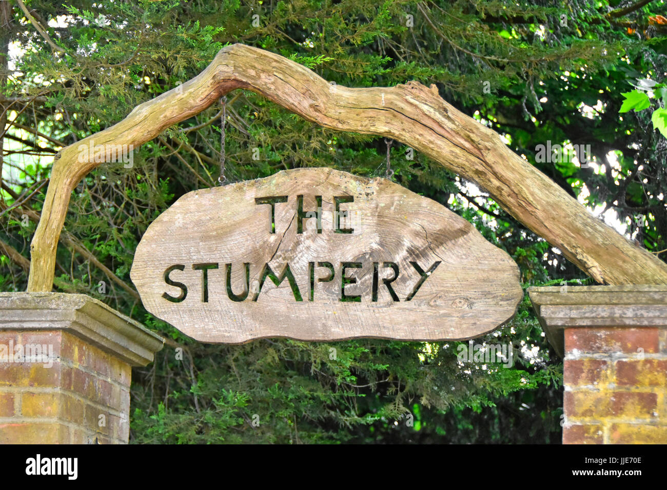 Stumpery entrance sign to shady woodland path devoted to artistically showing bits of dead rotting trees or timber & growing lichens ferns & similar Stock Photo