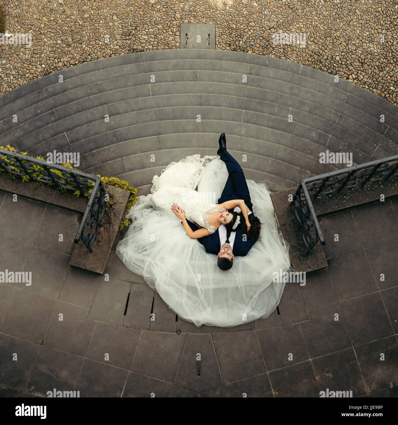 Close-up down view of the beautiful newlywed couple laying on the dress ...