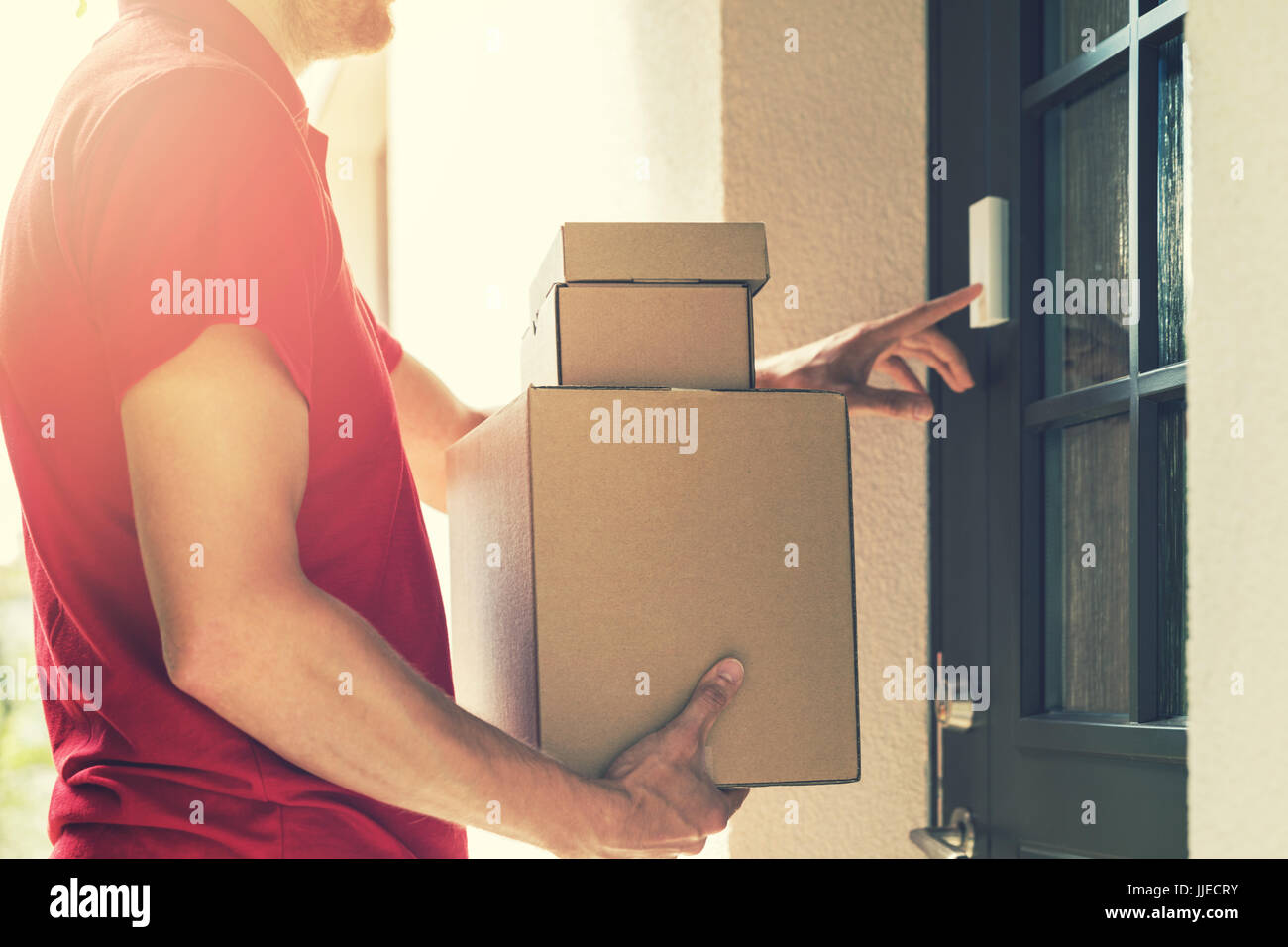 delivery service courier ringing the house doorbell with boxes in hands Stock Photo
