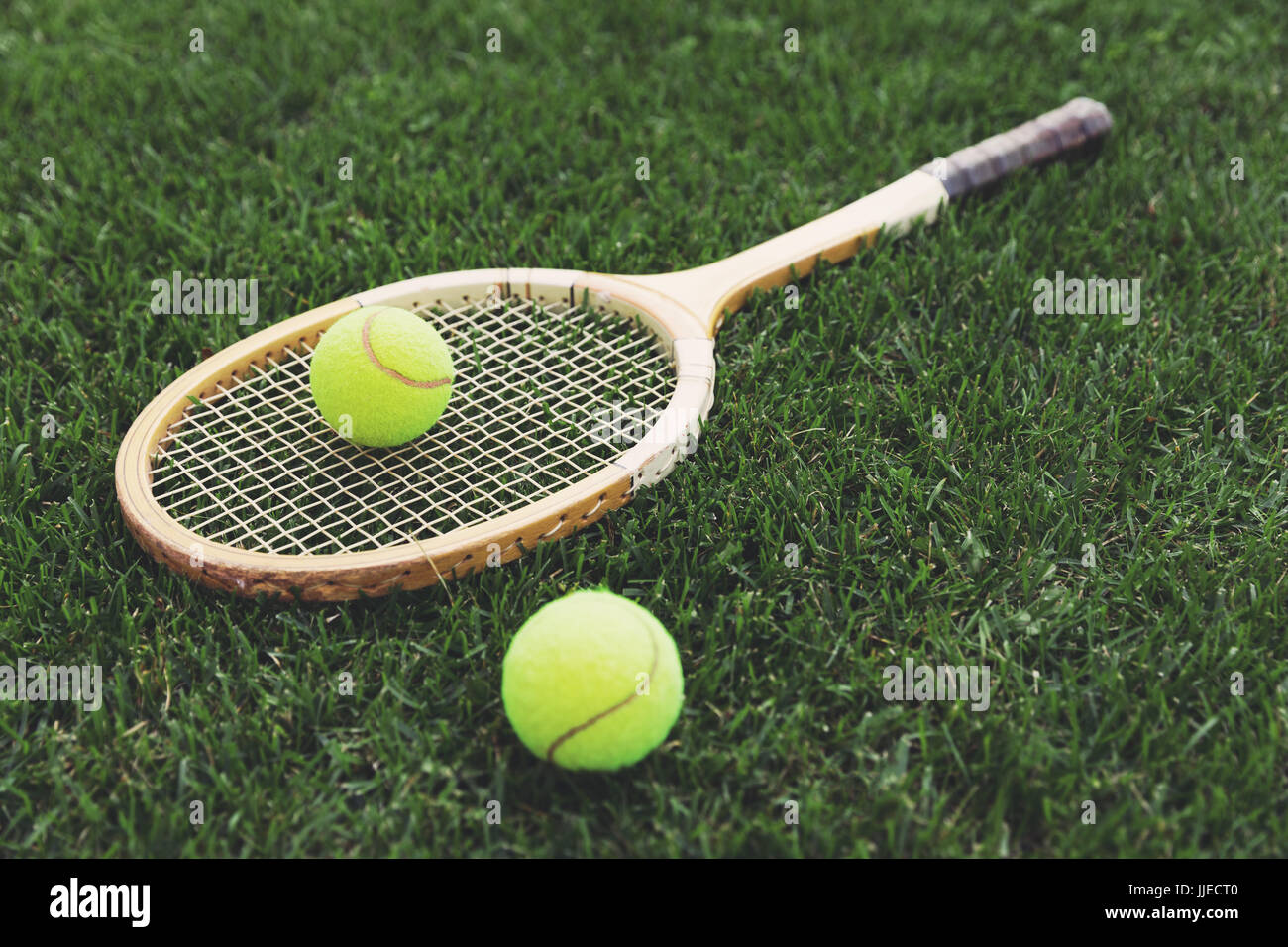 vintage wooden tennis racket on grass with balls Stock Photo
