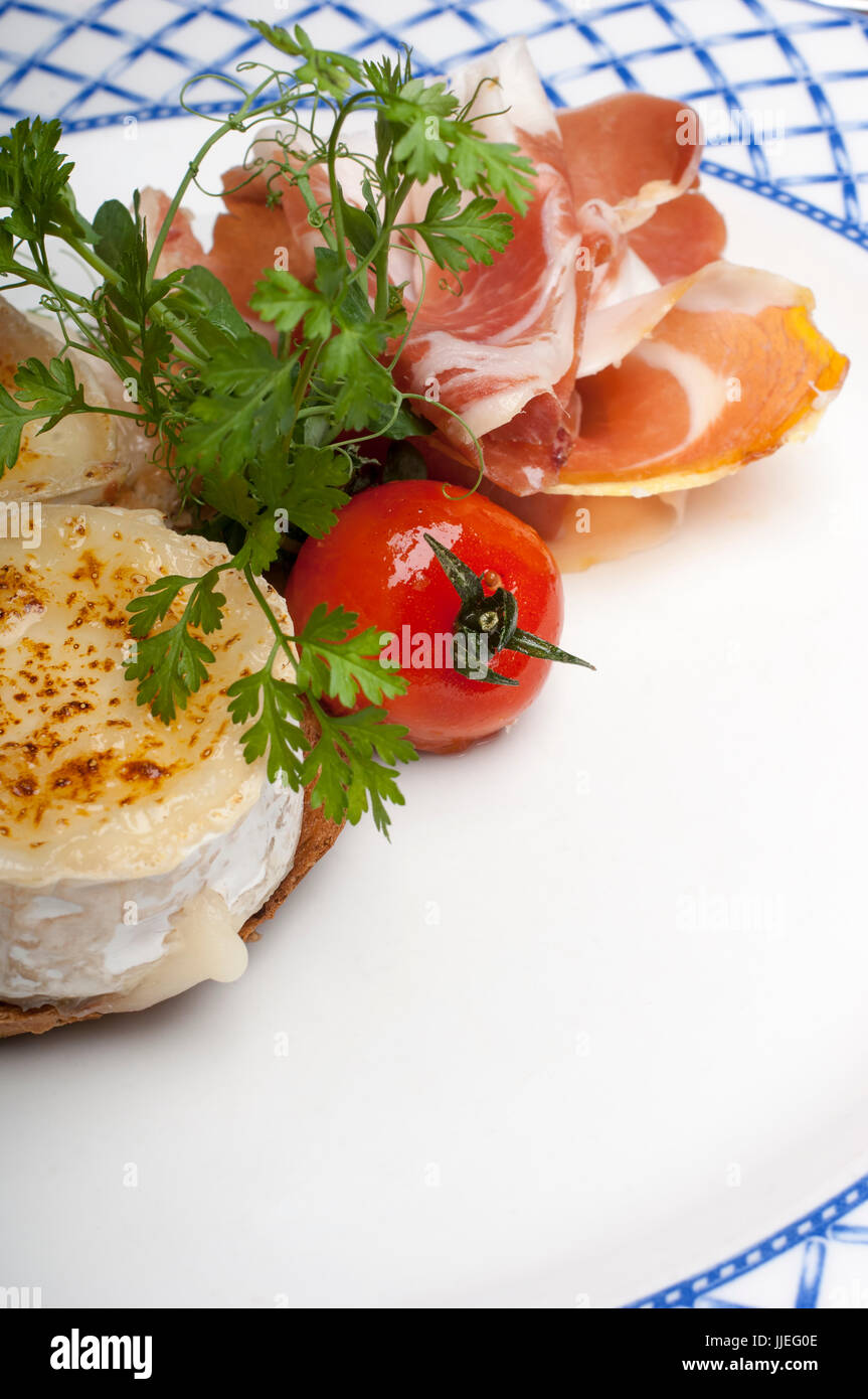 Roast Goat Cheese with Parma Ham and a Balsamic dressing on a white and