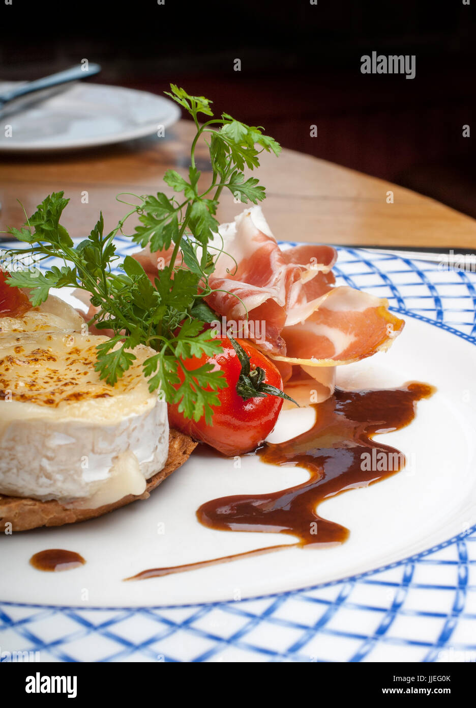 Roast Goat Cheese with Parma Ham and a Balsamic dressing on a white and