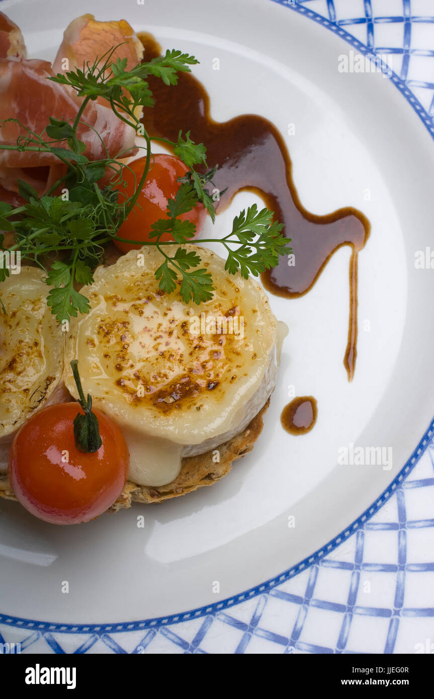 Roast Goat Cheese with Parma Ham and a Balsamic dressing on a white and