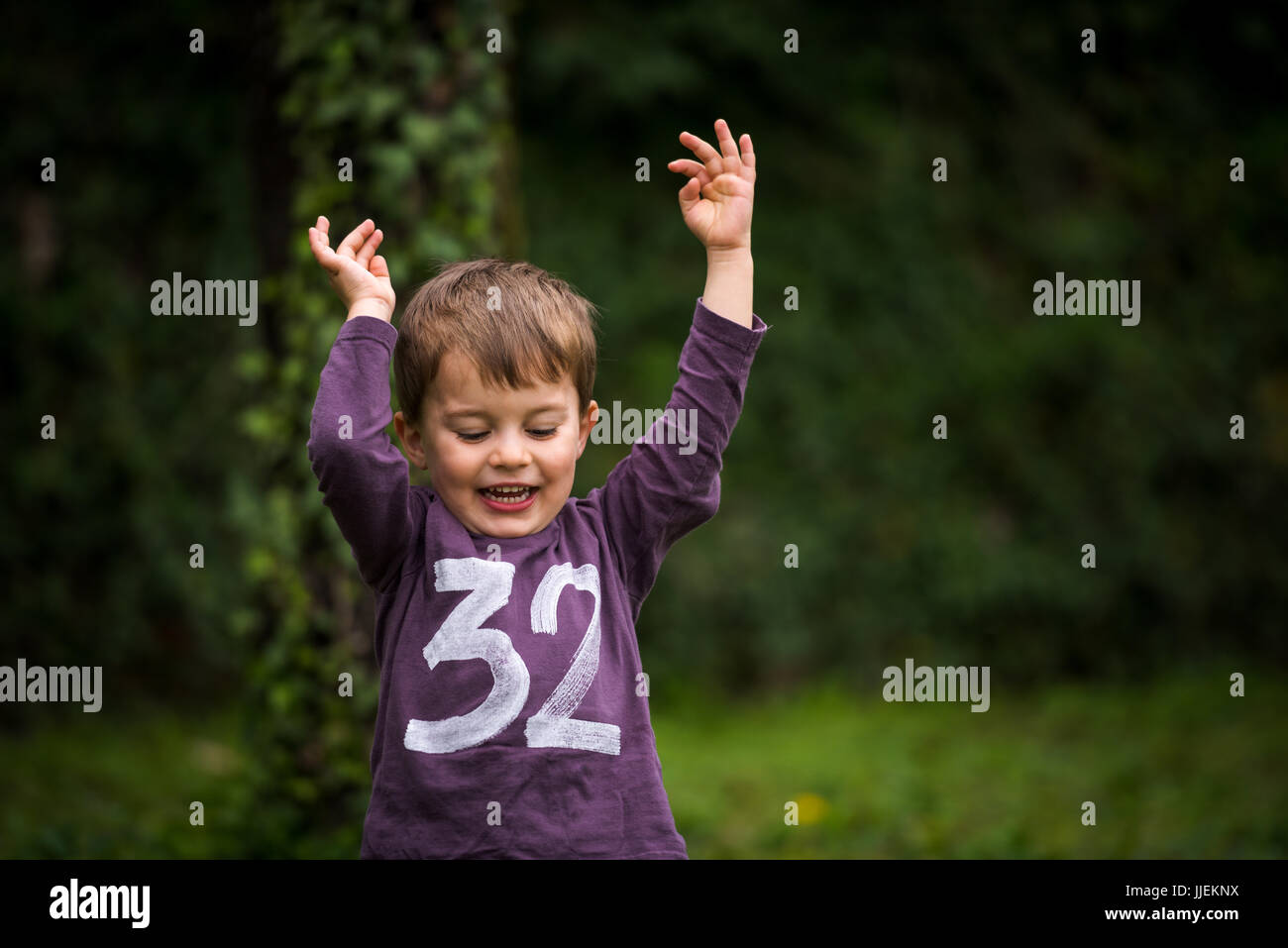 Happy cute little boy at park with raised hands Stock Photo - Alamy