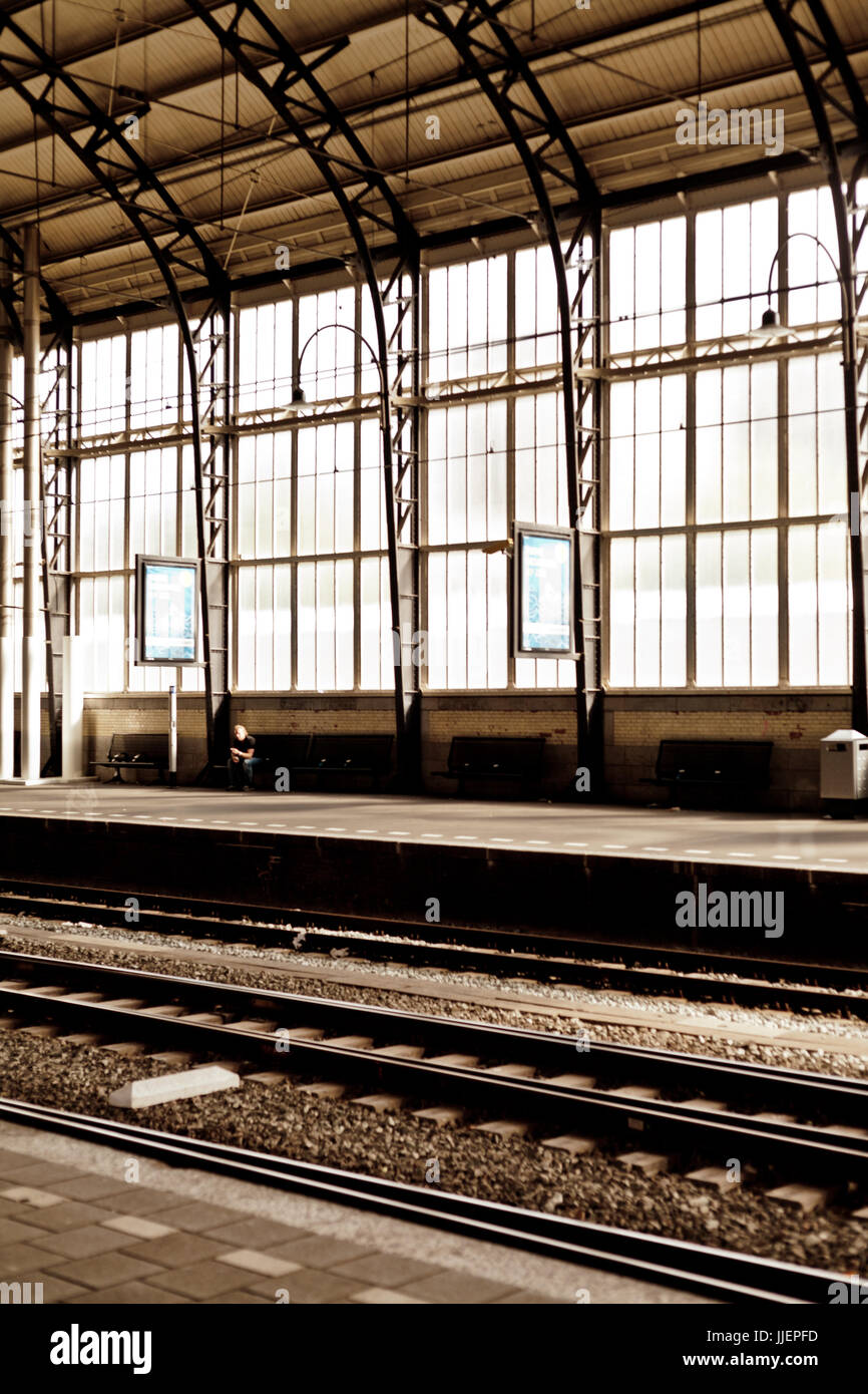A man alone at the empty train station with stained big window behind in Harlem Holland Stock Photo