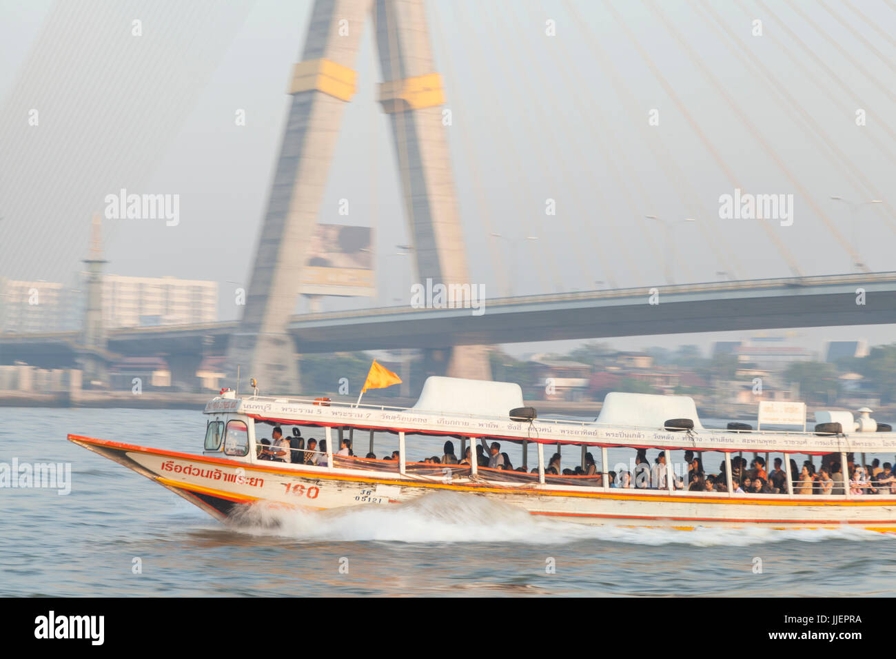 A water taxi speeds past on the Chao Phraya River below the cable-stayed Rama VIII Bridge, Phra Nakhon District, Bangkok, Thailand. Stock Photo