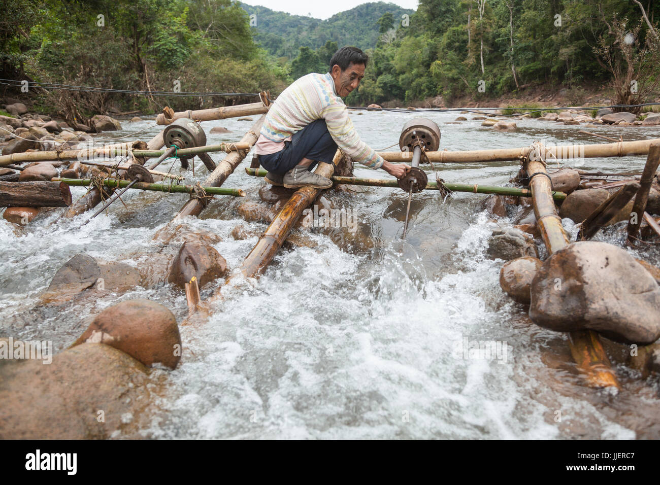A man adjusts the (boat) propeller on a micro hydro turbine in the flow of the Nam Ou River at Ban Sop Kha, Laos. The turbines are used by villages all along the river to generate electricity, at least during the dry season when the water level is low enough to mount them to the river bed. Stock Photo