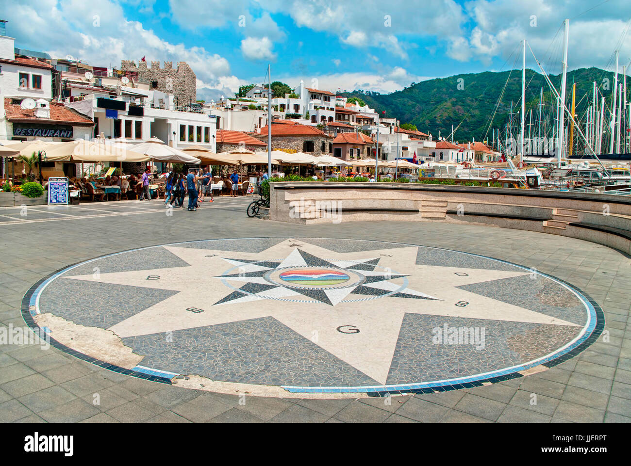 small square with mosaic compass with people walking along bar and restaurant street and marina in old part of marmaris, turkey Stock Photo