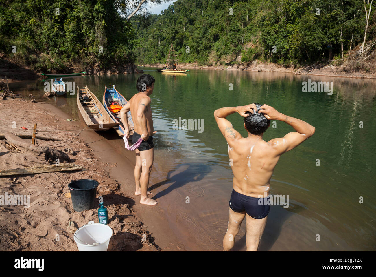 Chinese workers bathe as a drill rig collects core samples in a natural constriction of the Nam Ou River where Dam #7 is planned for construction, within Phou Den Din National Protected Area, Laos (despite Sino Hydro's charter not to impact country's national parks with their hydropower development). Stock Photo