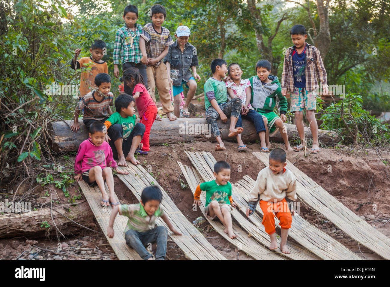 Children play and slide down split bamboo mats on the beach in Muang Hat Hin, Laos. Stock Photo