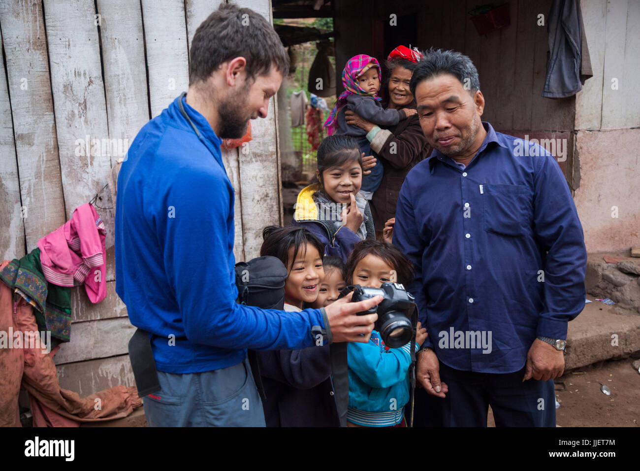 Robert Hahn shows a crowd of curious bystanders photos of themselves on the back of his camera in Muang Hat Hin, Laos. Stock Photo