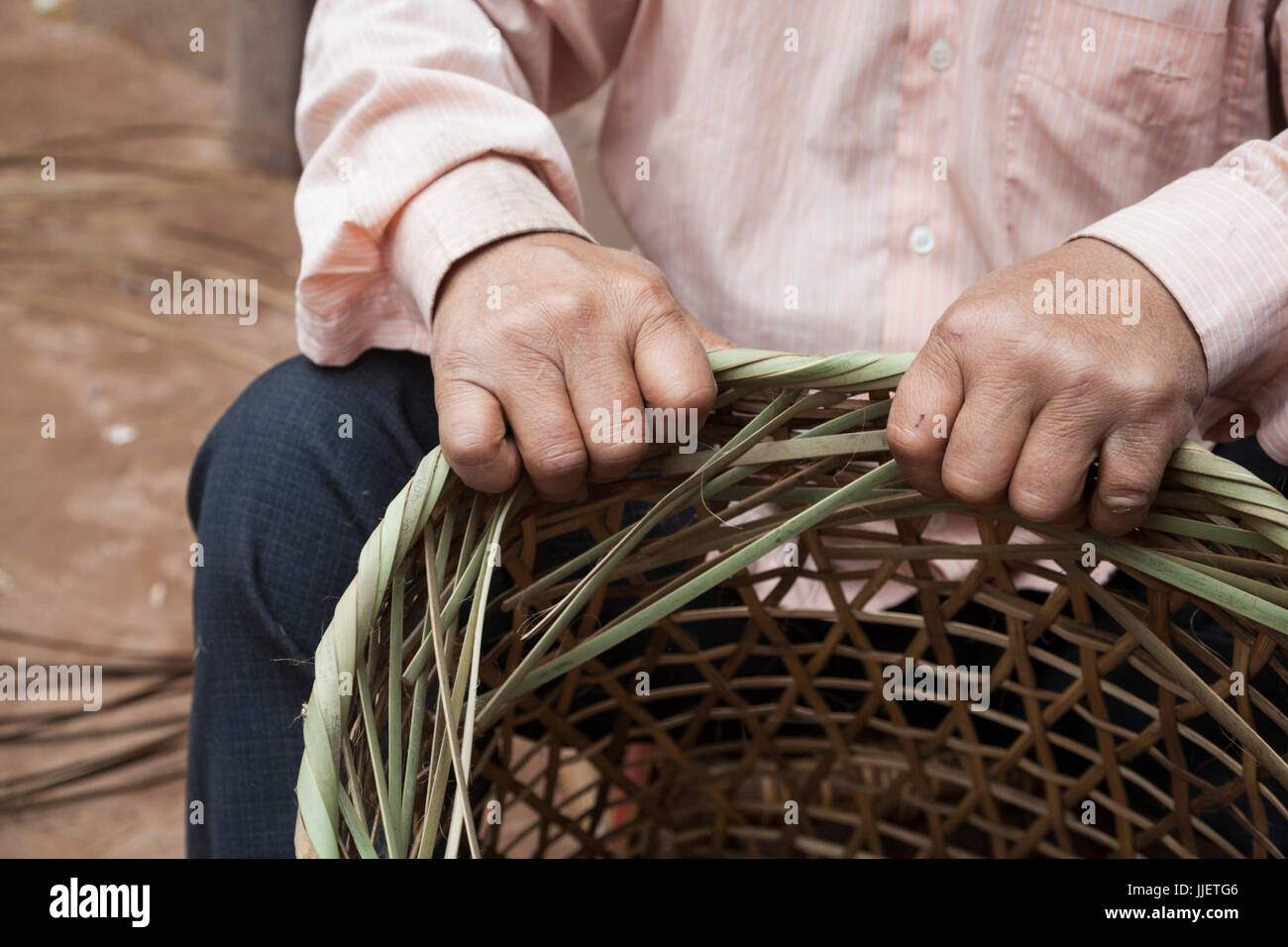 A man finishes a wicker basket in Muang Hat Hin, Laos. Stock Photo