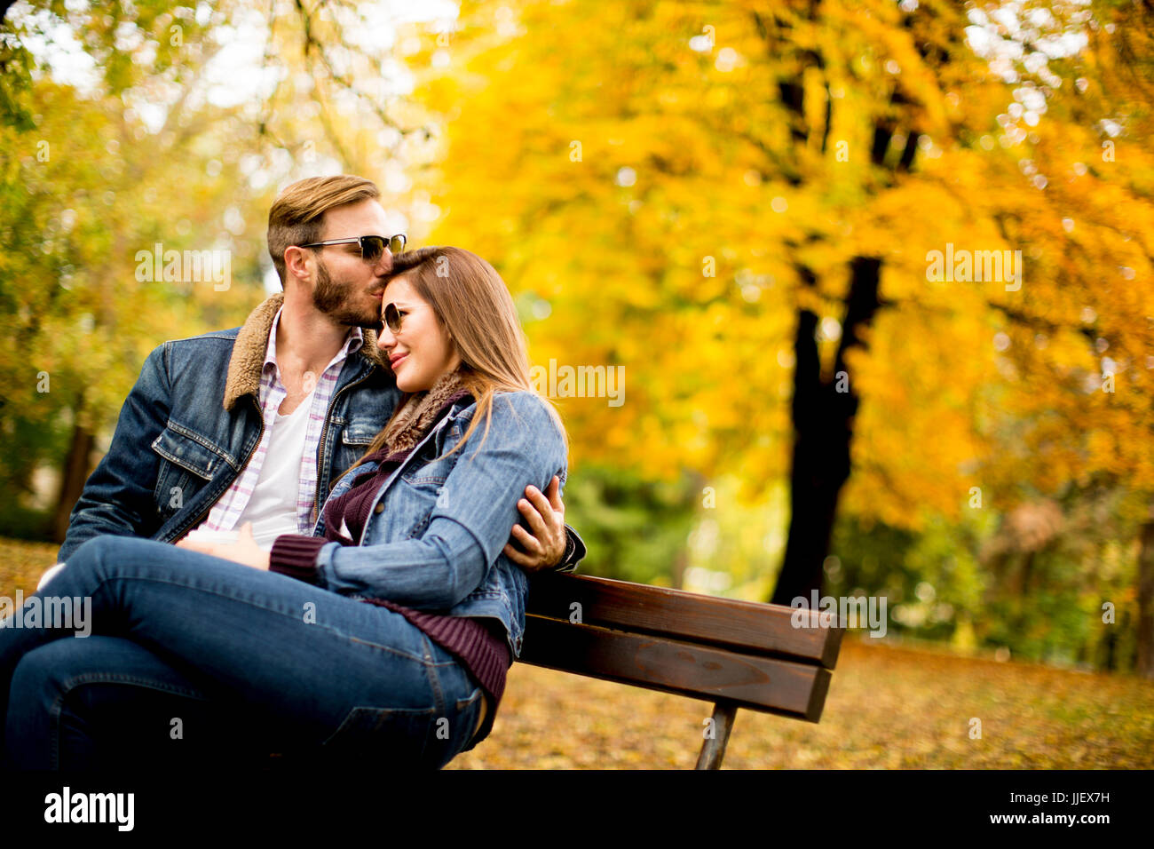 View at young loving couple on a bench in autumn park Stock Photo - Alamy