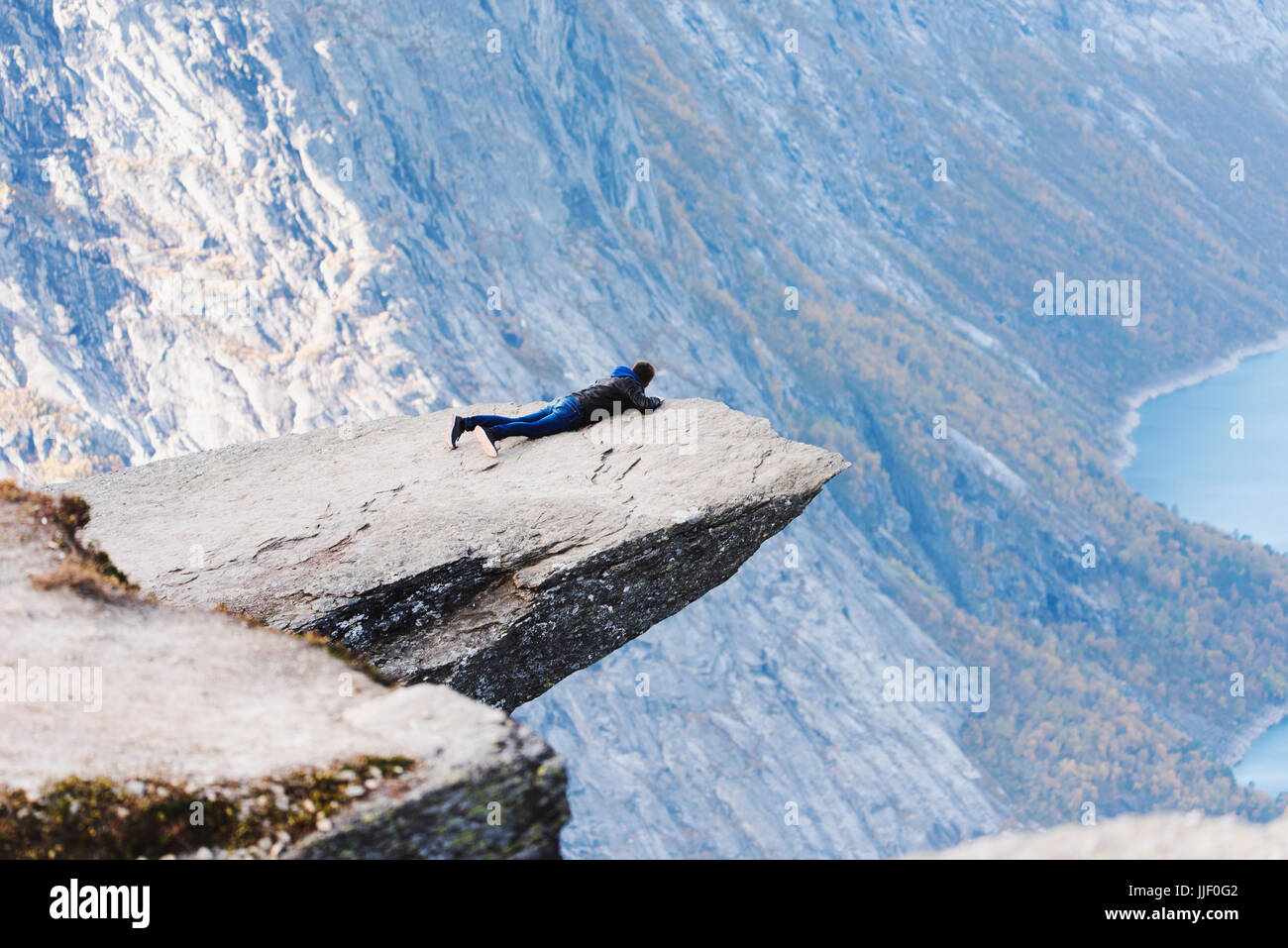 Man lying on a rocky outcrop, Trolltunga, Odda, Hordaland, Norway Stock Photo